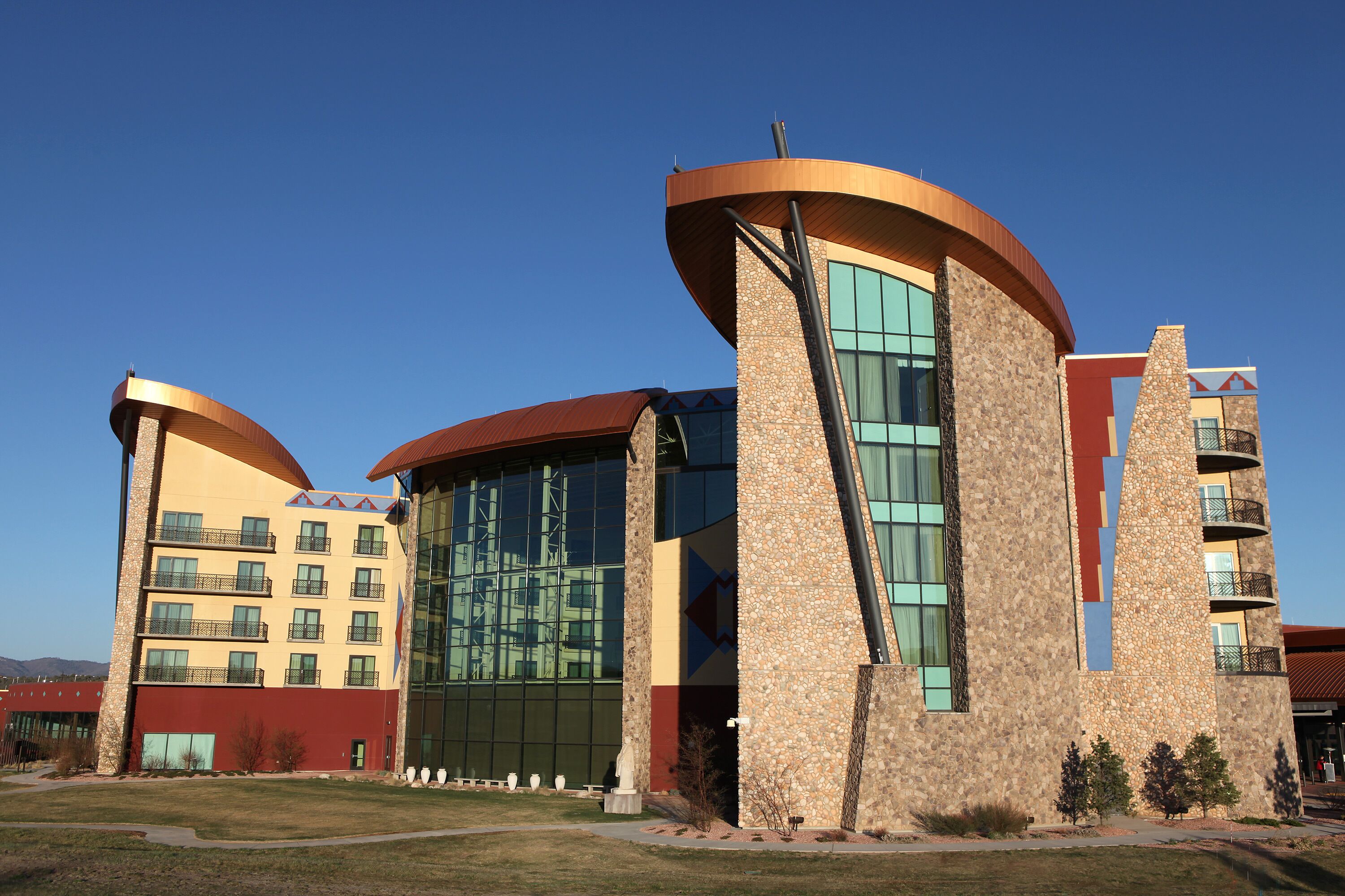 A multi-story hotel with a modern design, featuring a central glass facade and a unique curved roof structure.