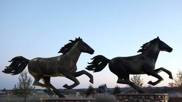 Two bronze horse statues on pedestals in an outdoor setting.