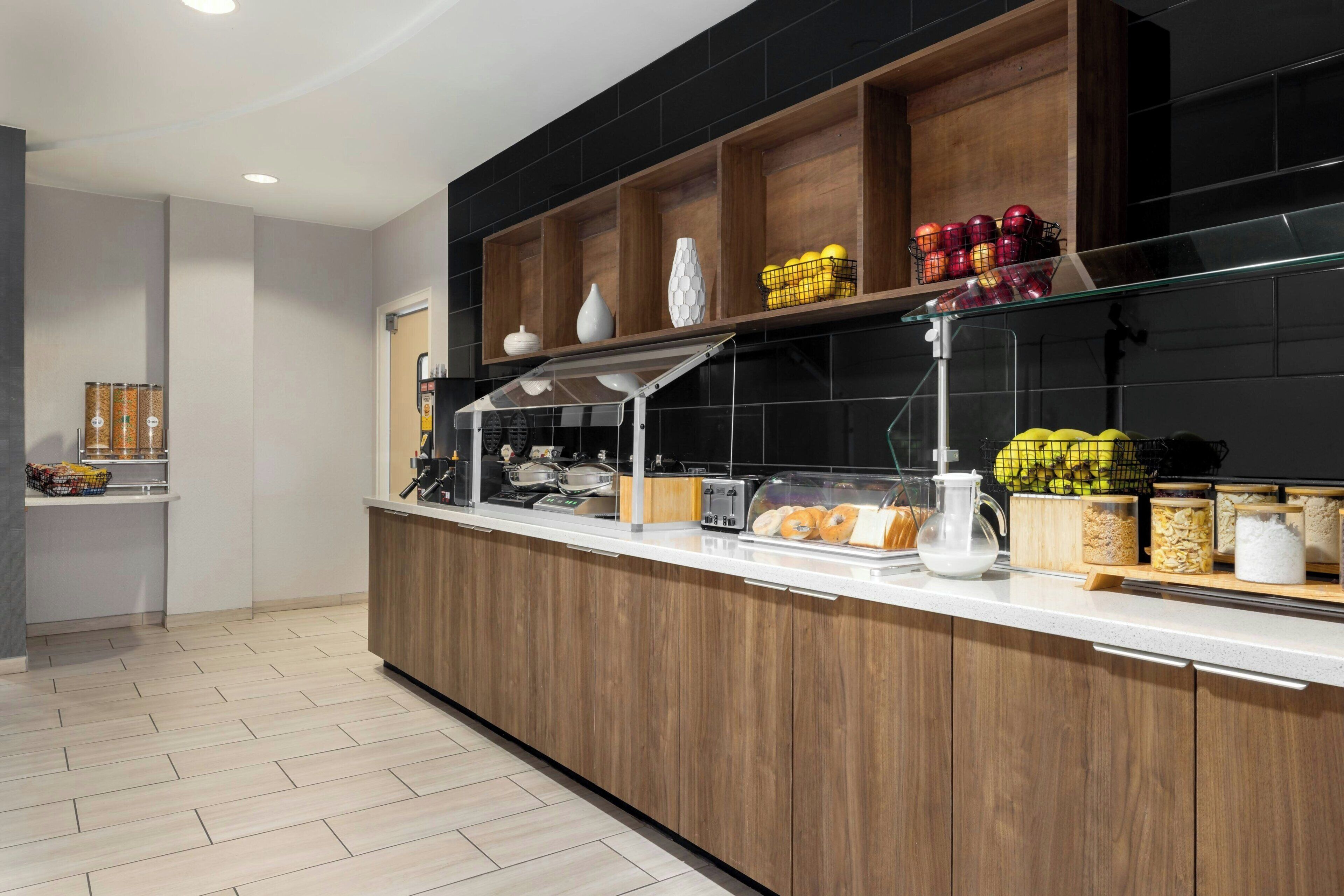 A modern kitchen area with a wooden counter, various food items, and a coffee machine.
