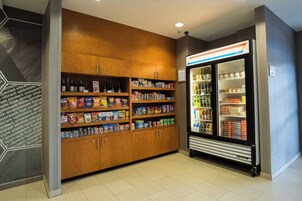 A snack and beverage vending area with a refrigerator and shelves stocked with snacks and drinks.