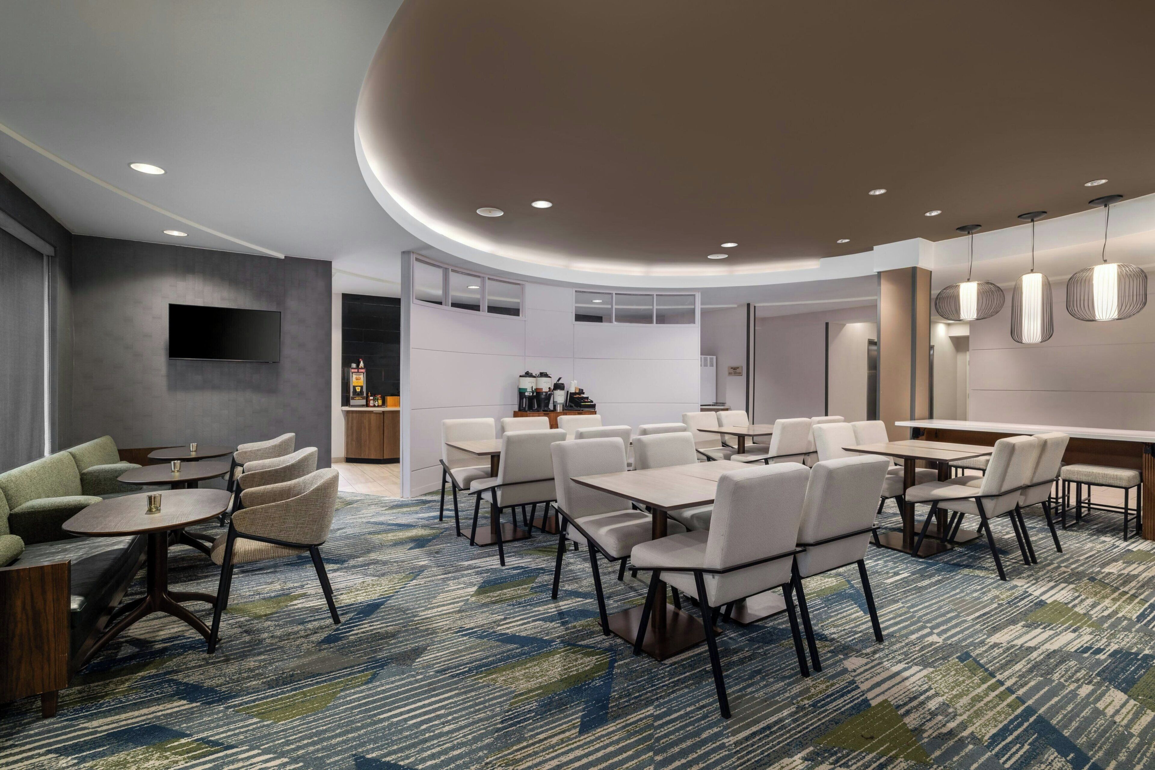 A modern hotel lobby with a seating area, a bar, and a conference room.