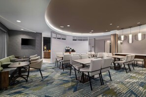 Een moderne hotellobby met een zithoek, een bar en een congreszaal.