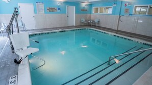 Una piscina interior con agua cristalina, señales de seguridad y una silla de socorrista.