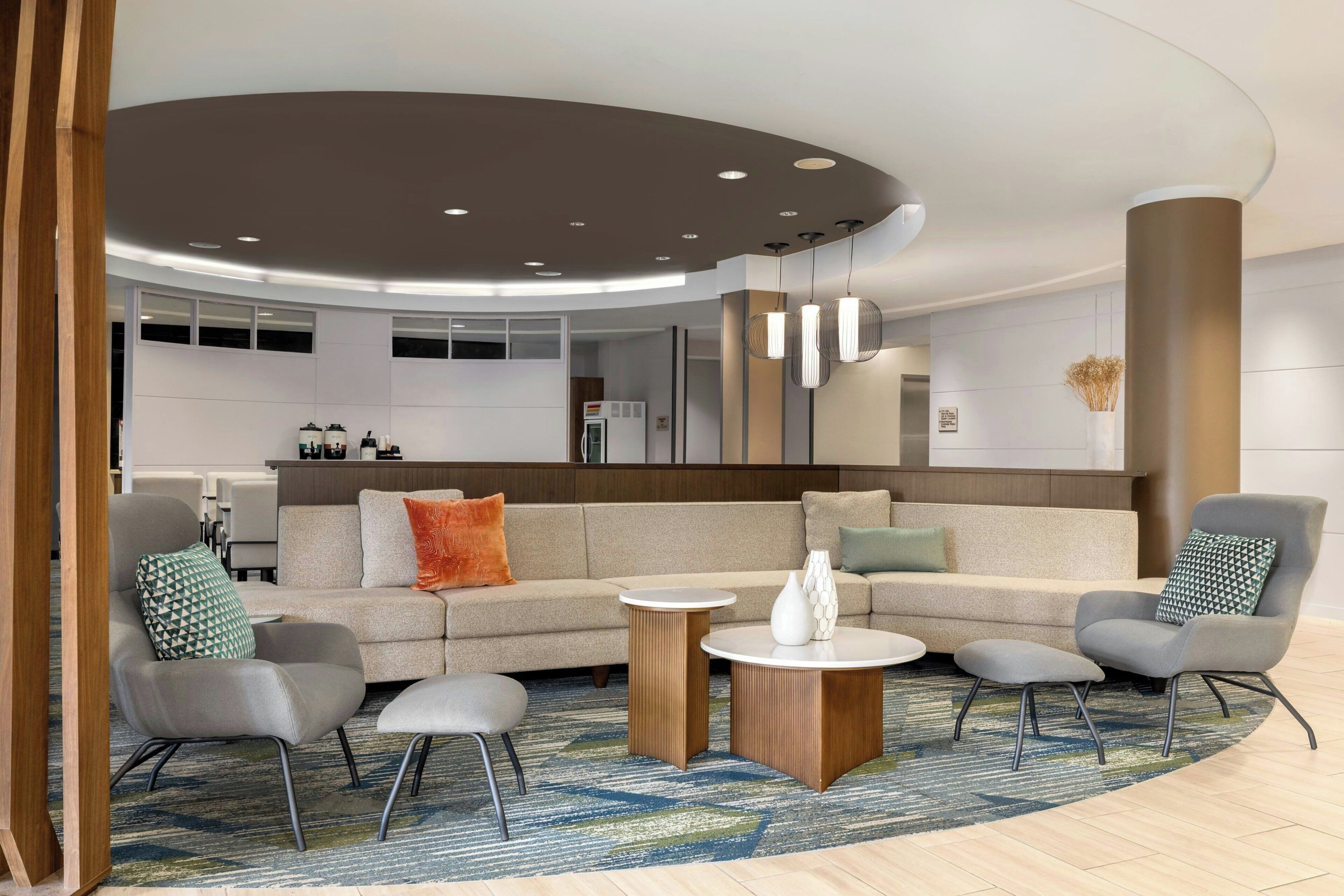 A modern living room with a sofa, armchairs, a coffee table, and a rug.