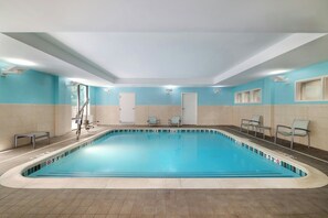 A large indoor swimming pool with clear water, surrounded by beige and light blue walls, and equipped with a diving board and lounge chairs. - Springhill Suites by Marriott Winston-Salem Hanes Mall (Winston-Salem)