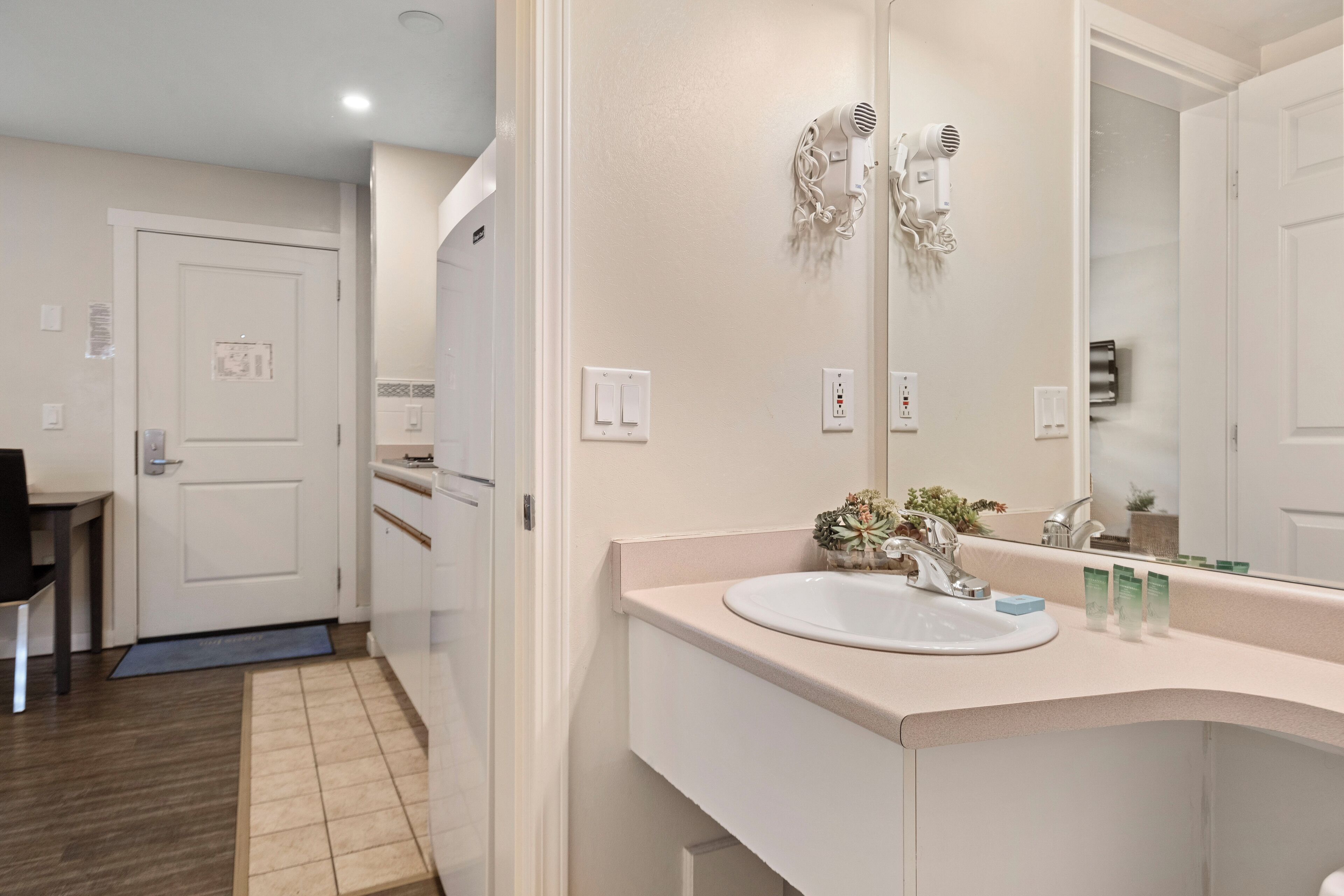 A bathroom with a sink, mirror, and hair dryer mounted on the wall.