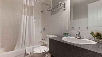 A modern bathroom with a bathtub, toilet, sink, and a shower curtain.