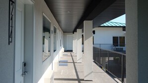 A covered corridor with doors, a metal railing, and a building in the background. - Oasis Inn (Kelowna)