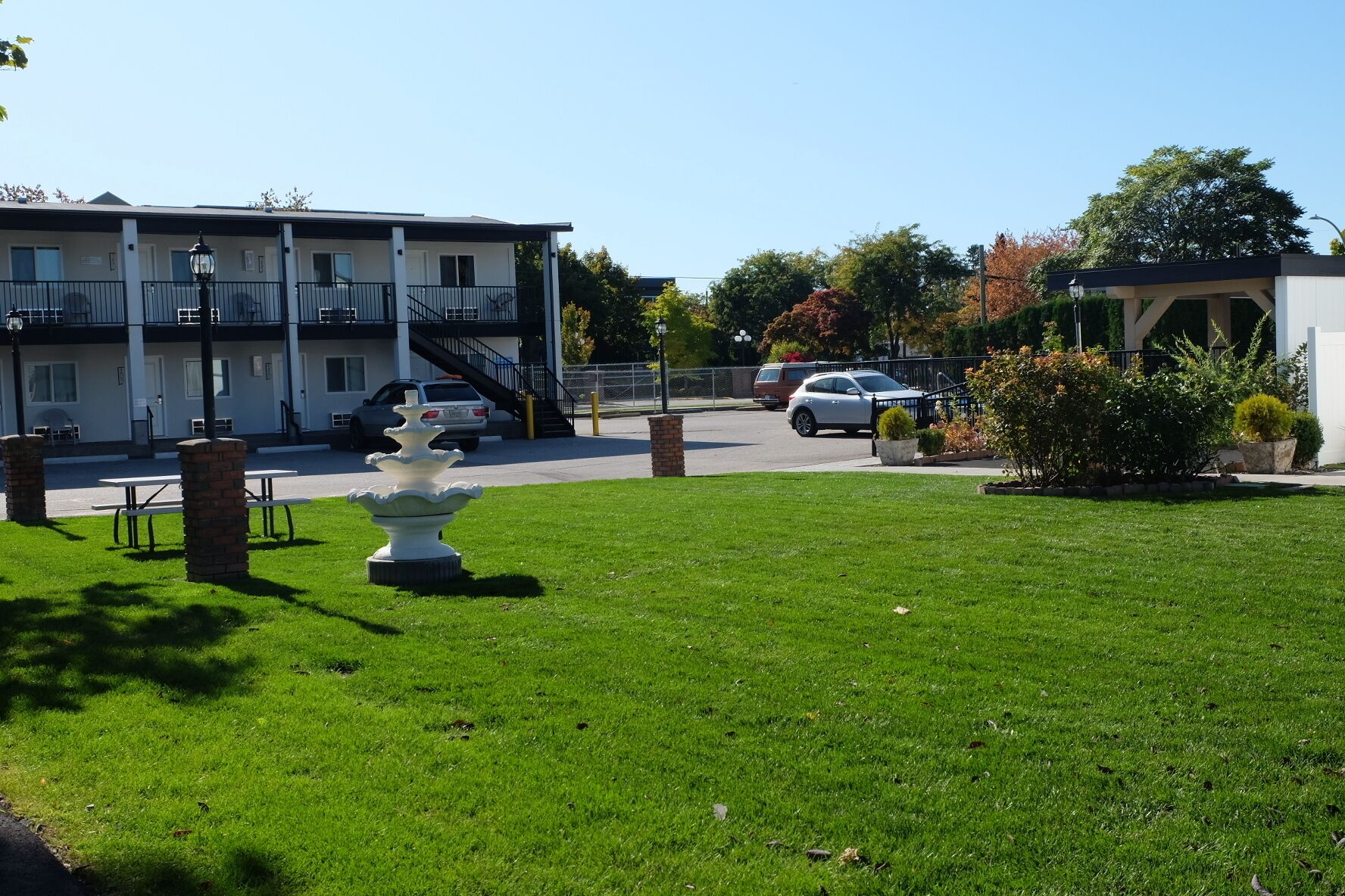 A hotel with a parking area, a fountain, and a well-maintained lawn.