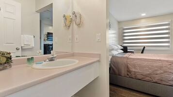 A modern bathroom with a sink, mirror, towel rack, and a potted plant.
