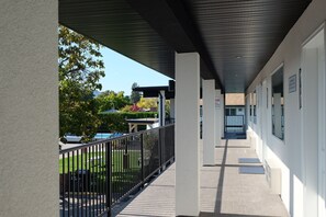 A covered corridor with a metal railing, leading to a building entrance.