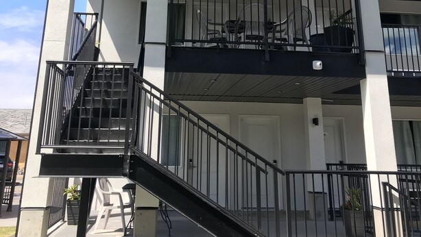 A two-story building with a covered outdoor area, a staircase, and a railing. - Oasis Inn (Kelowna)
