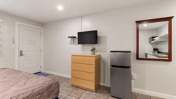 Una camera da letto con un letto, una cassettiera, una televisione e un frigorifero.
