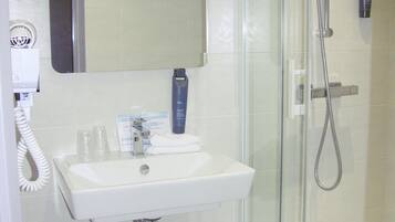 A bathroom with a white sink, a glass shower enclosure, and a mirror above the sink.