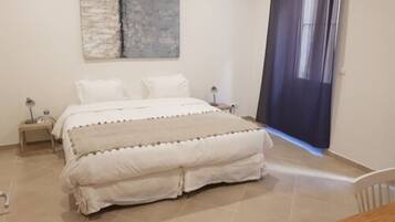 Un dormitorio con cama, mesitas de noche, lámpara y un cuadro en la pared.
