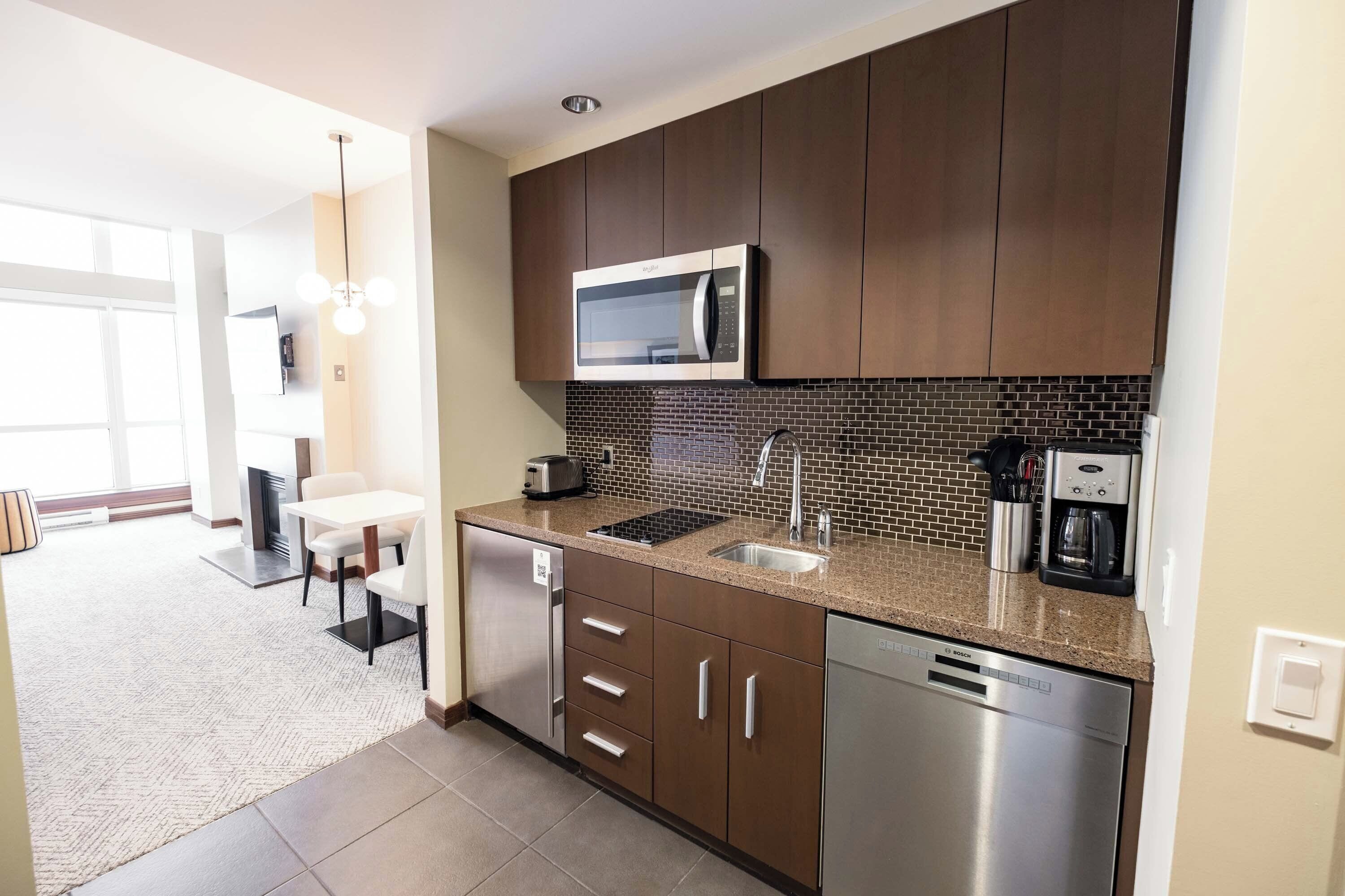 A modern kitchen with dark wooden cabinets, a stainless steel dishwasher, a microwave, and a coffee maker.