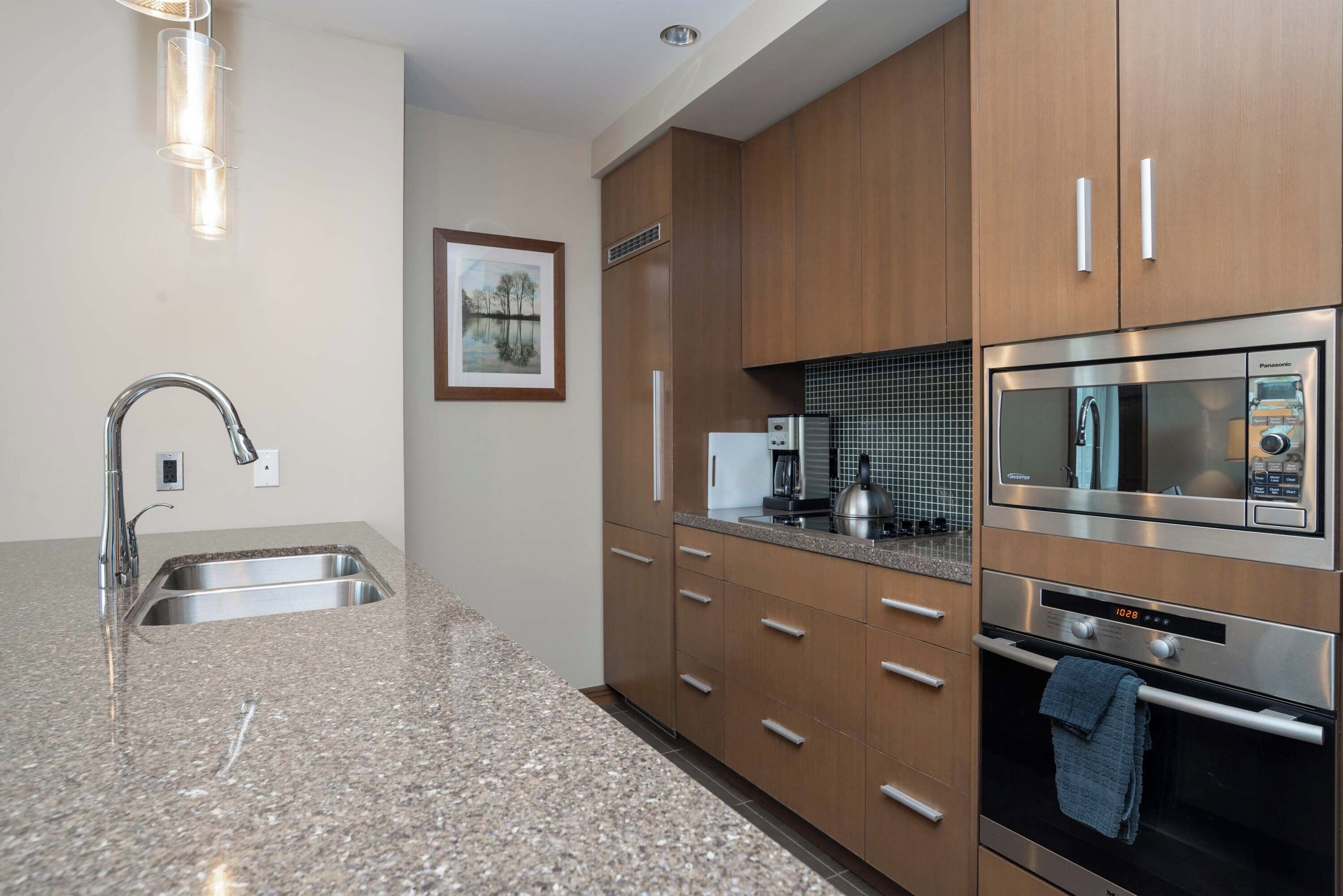 A modern kitchen with granite countertops, stainless steel appliances, and wooden cabinets.