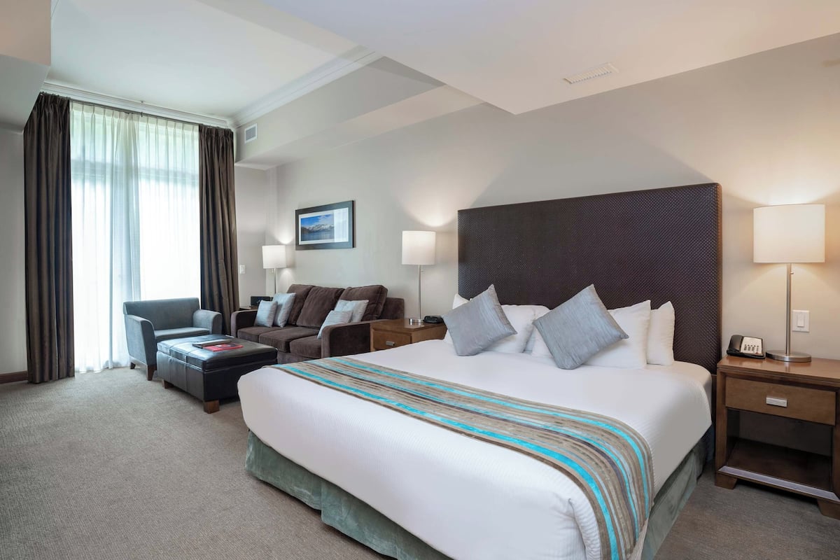 Een hotelkamer met een groot bed, twee sofa’s, een kleine tafel en een nachtkastje met een lamp.