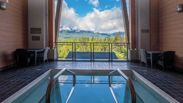 Ein Poolbereich mit Bergblick, Holzwänden und Außenmöbeln.