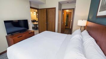 A hotel room with a bed, a TV on a wooden dresser, a lamp, and a mirror.