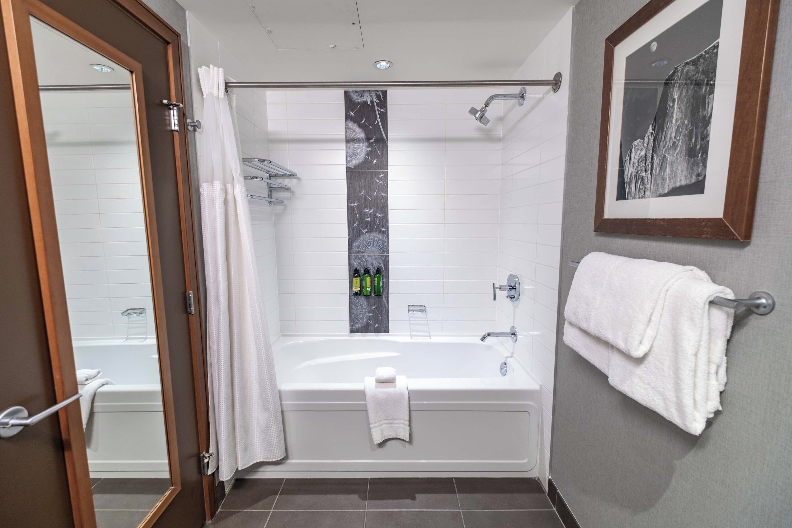 Ein modernes Badezimmer mit Badewanne, Dusche und einem gerahmten Bild an der Wand.