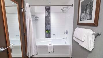 Ein modernes Badezimmer mit Badewanne, Dusche und einem gerahmten Bild an der Wand.