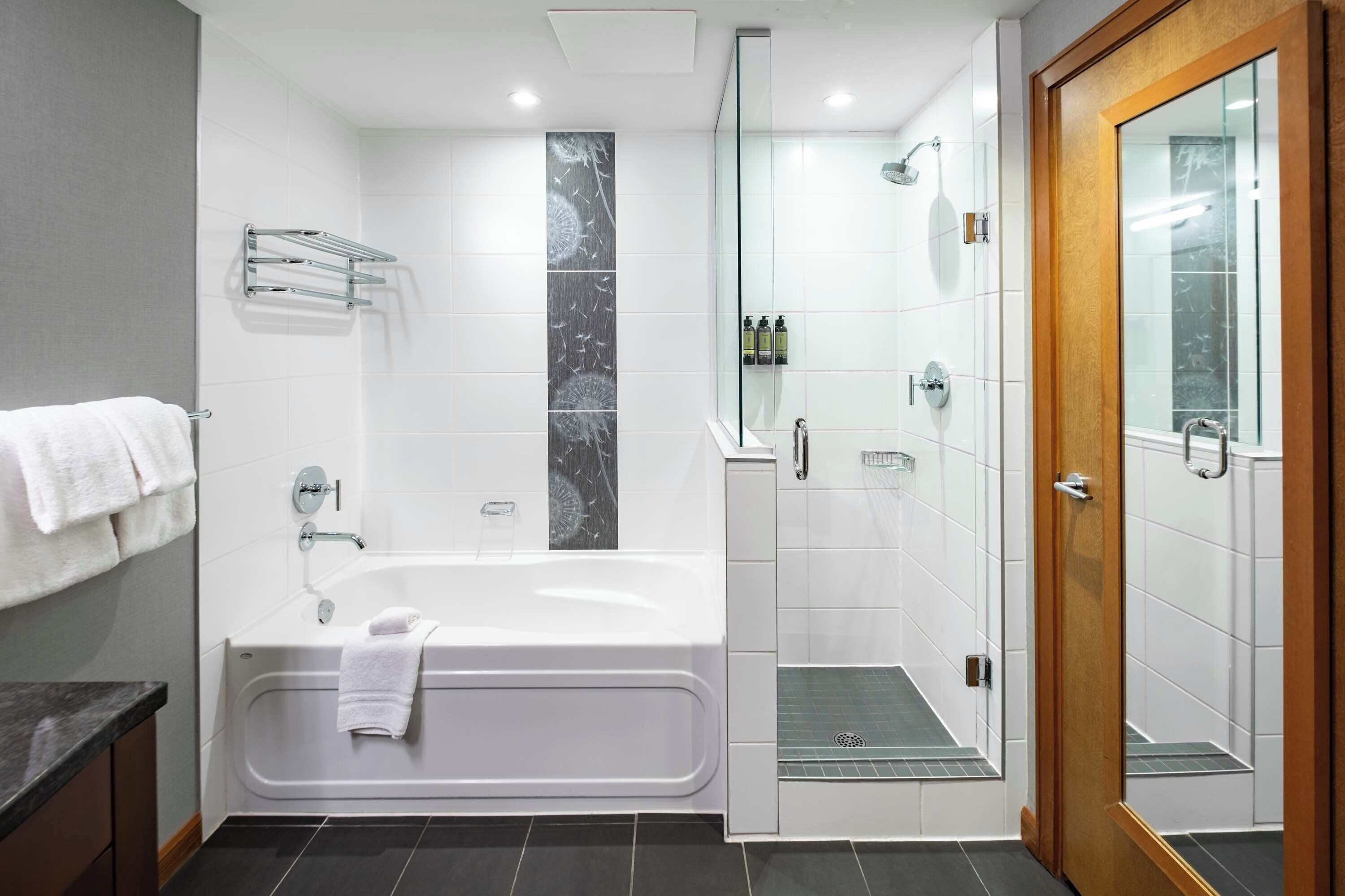 A modern bathroom with a bathtub, shower, and glass-enclosed shower stall.