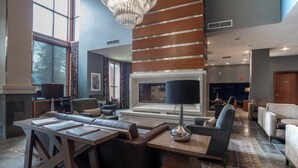 Eine geräumige Lobby mit großzügiger Sitzecke, Kamin und moderner Kristallleuchter.