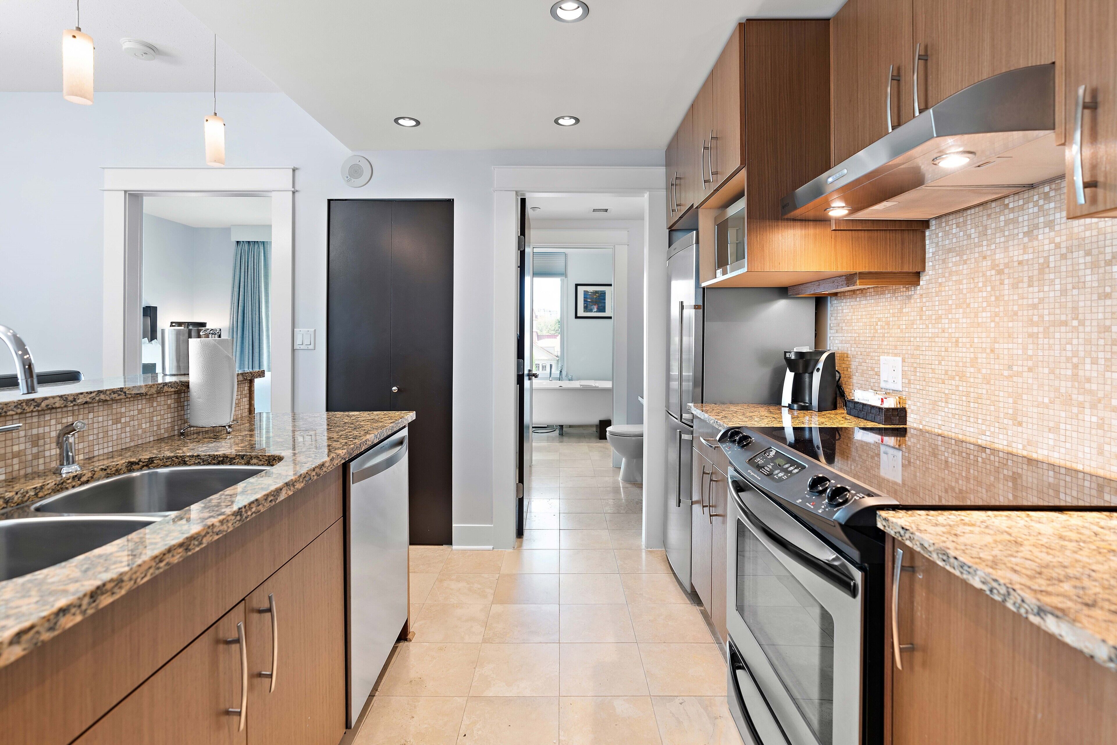 A modern kitchen with granite countertops, stainless steel appliances, and wooden cabinets.