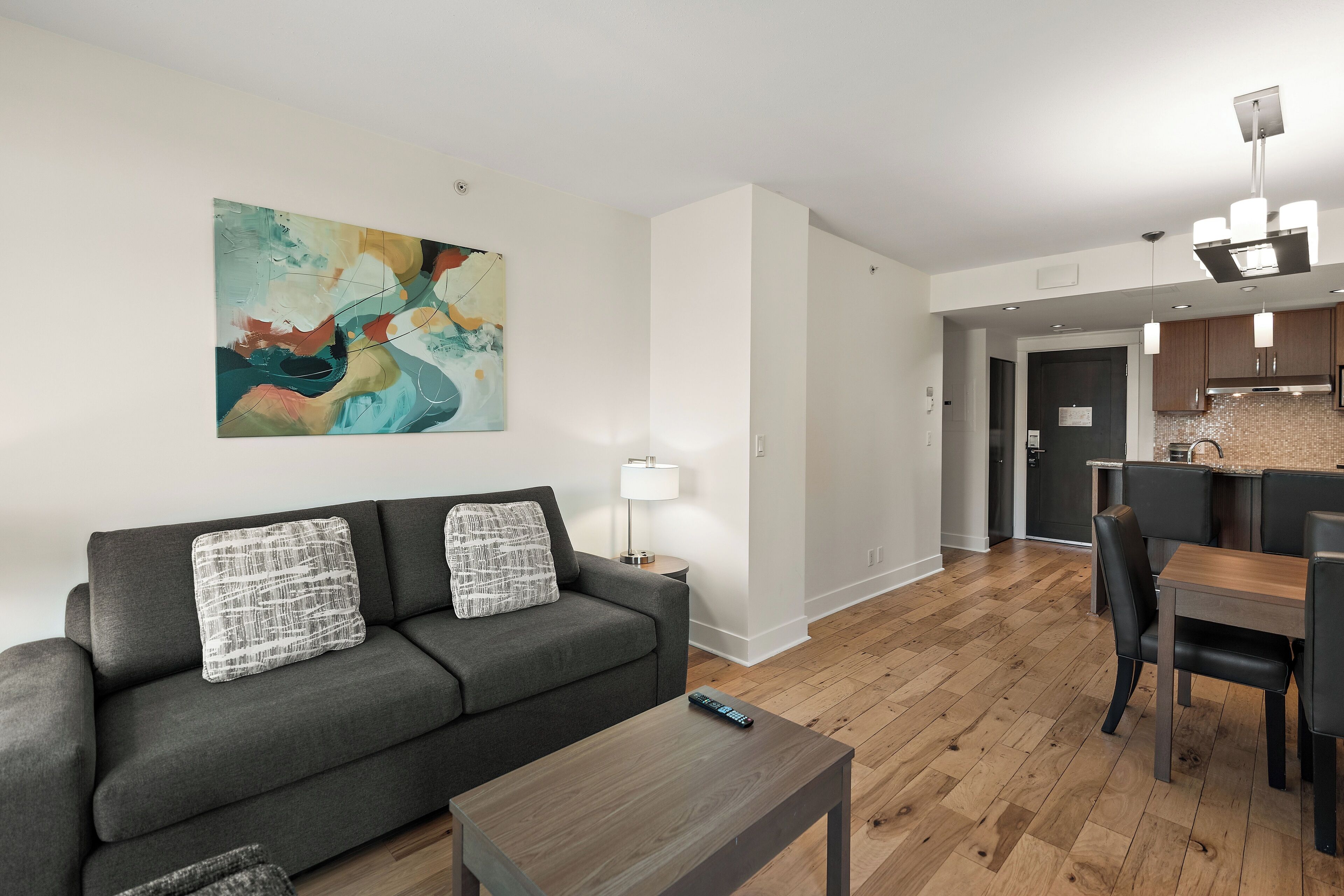 Un salon moderne avec un canapé gris, une table basse en bois et un coin repas comprenant une table et des chaises.