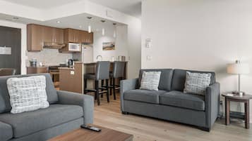 Uma sala de estar moderna com um sofá cinzento, uma mesa de centro de madeira e uma luminária.