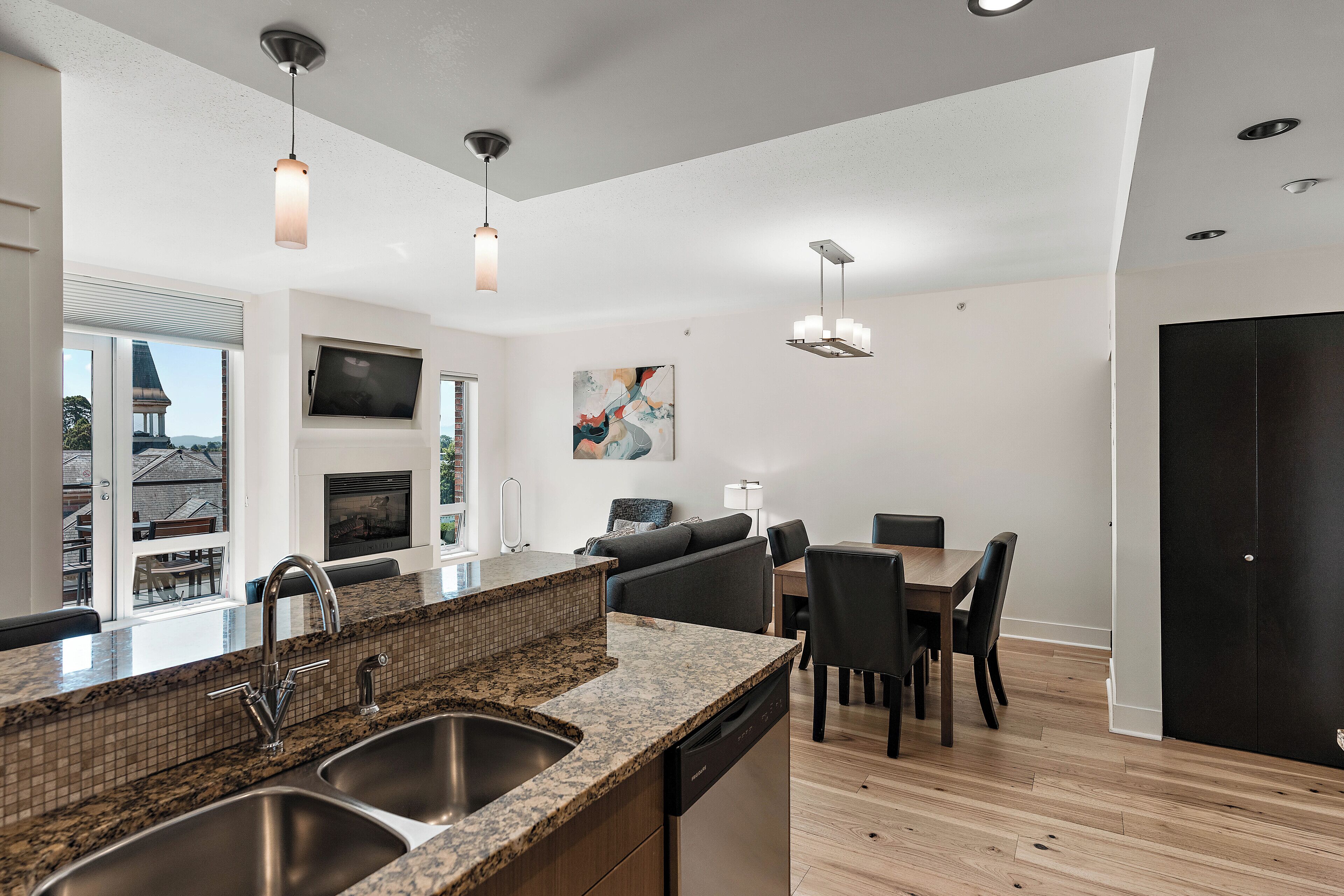A modern kitchen with granite countertops, stainless steel appliances, and pendant lighting.