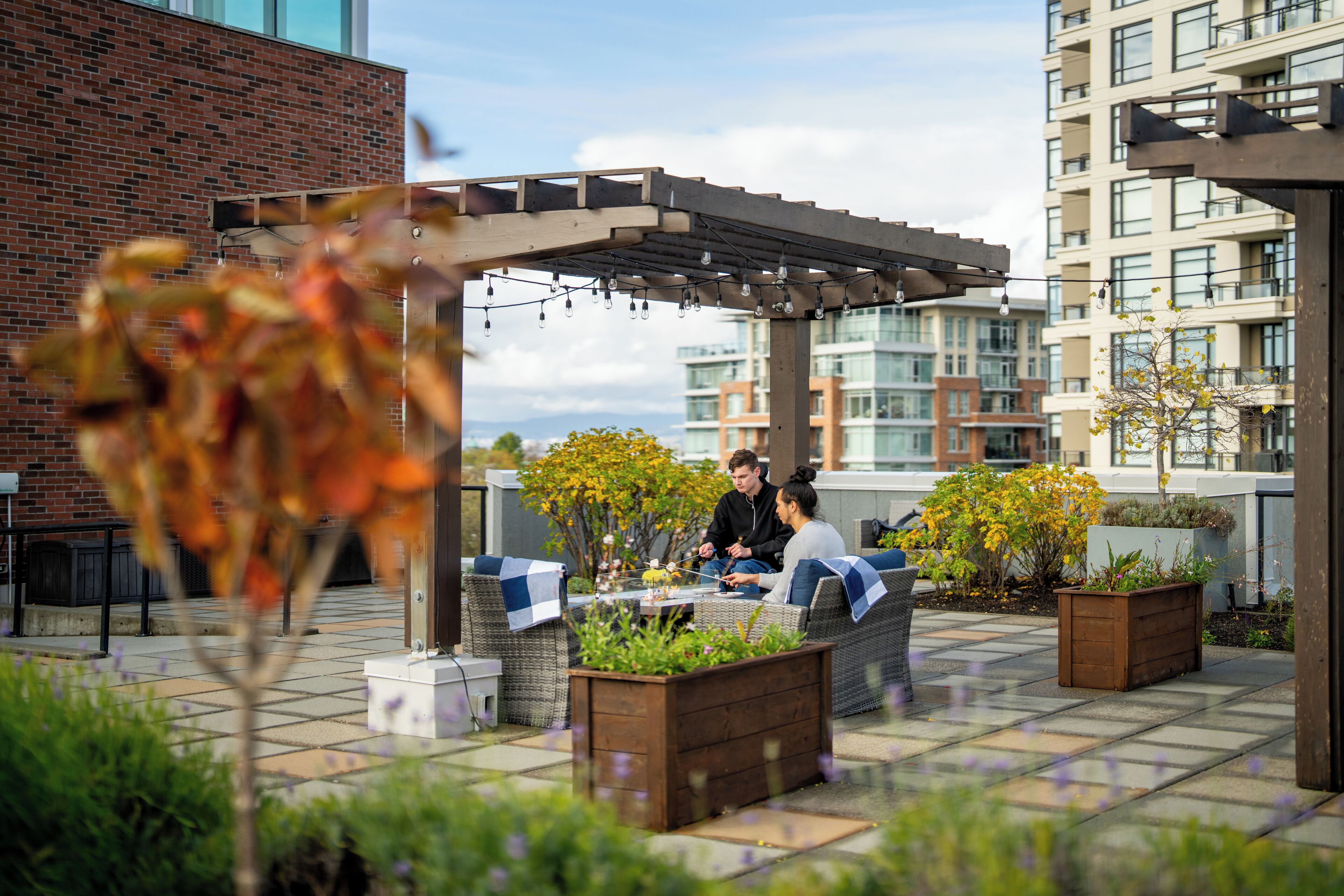 Eine Dachterrasse mit Sitzgelegenheiten im Freien, einer Pergola und Topfpflanzen.