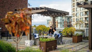 Eine Dachterrasse mit Sitzgelegenheiten im Freien, einer Pergola und Topfpflanzen.