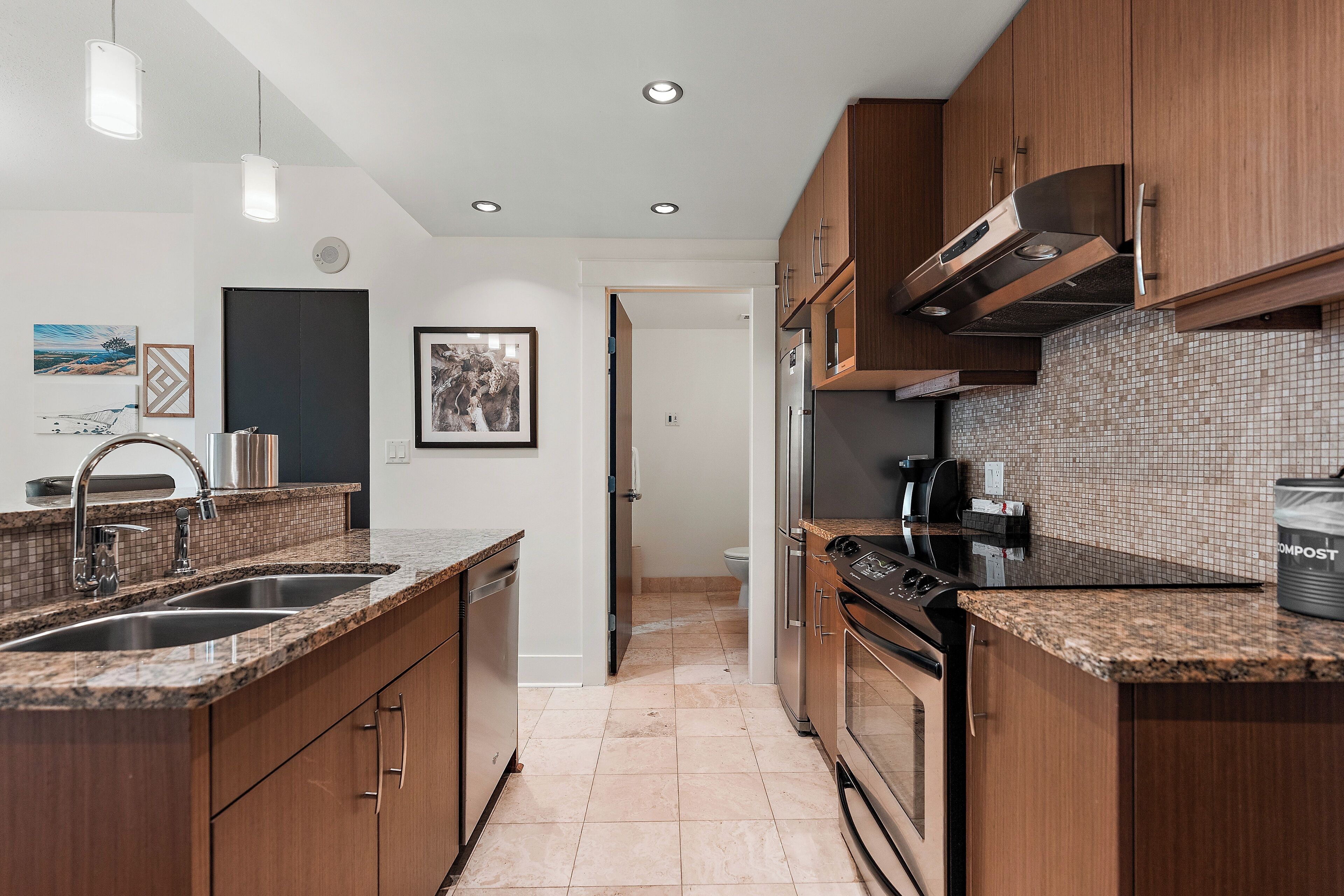 Una cocina moderna con encimeras de granito, electrodomésticos de acero inoxidable y armarios de madera.