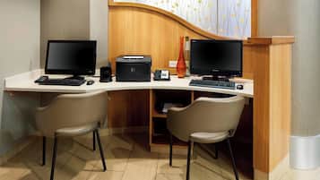 Un escritorio moderno de oficina con dos monitores, una impresora y dos sillas.