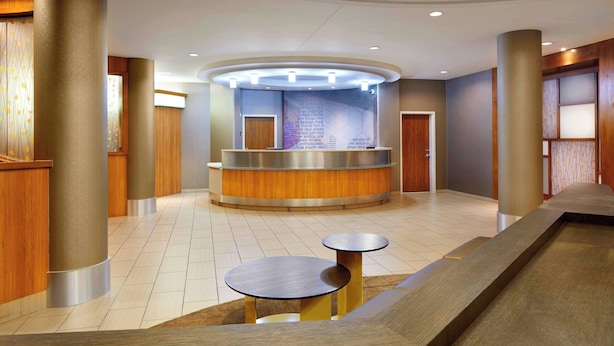 A reception area with a curved counter, two small tables, and a tiled floor. - SpringHill Suites by Marriott Houston NASA/Webster (Webster)