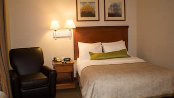 Una habitación de hotel con una cama, una silla, una mesita de noche con teléfono y dos lámparas de pared.