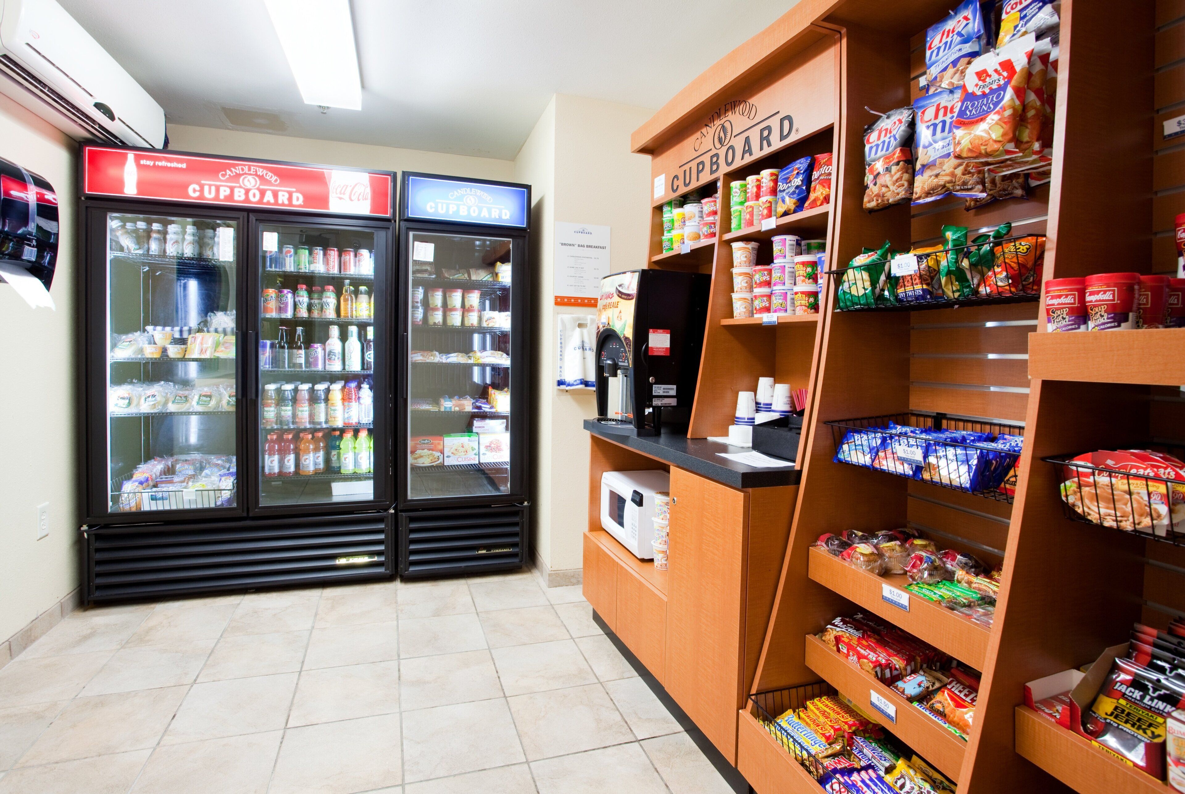 Een gemakswinkel met gekoelde drankautomaten, een koffieapparaat en schappen vol snacks en dranken.