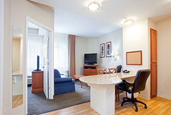 A hotel room with a living area, a dining table with chairs, a TV, and a small kitchenette. - Candlewood Suites Jacksonville by IHG (Jacksonville)