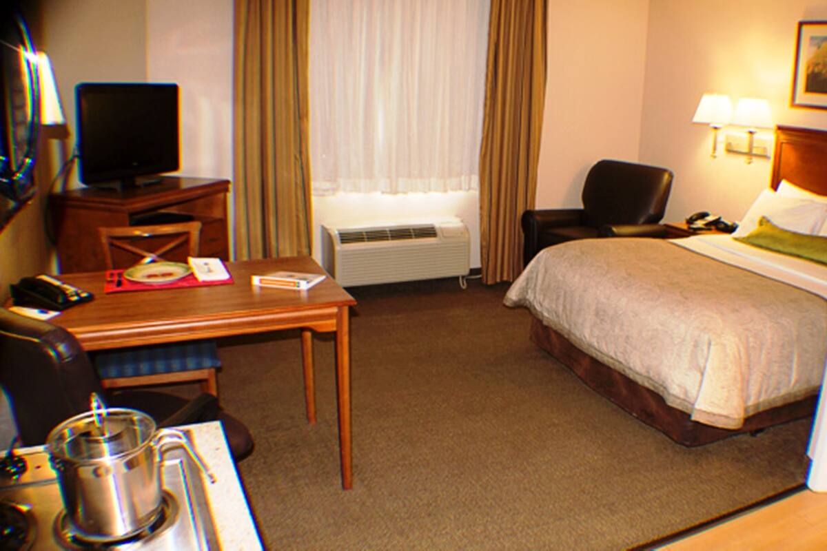 A hotel room with a bed, a desk, a chair, a television, and a coffee maker.