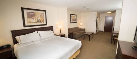 A hotel room with a large bed, a desk, a chair, and a television.