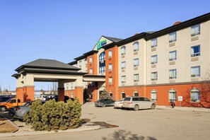 A hotel with a brick facade, multiple windows, and a parking lot with several cars. - Holiday Inn Express Hotel & Suites WHITECOURT by IHG (Whitecourt)