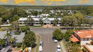 A residential area with houses, a road, and a body of water in the background. - At The Sound (Noosaville)
