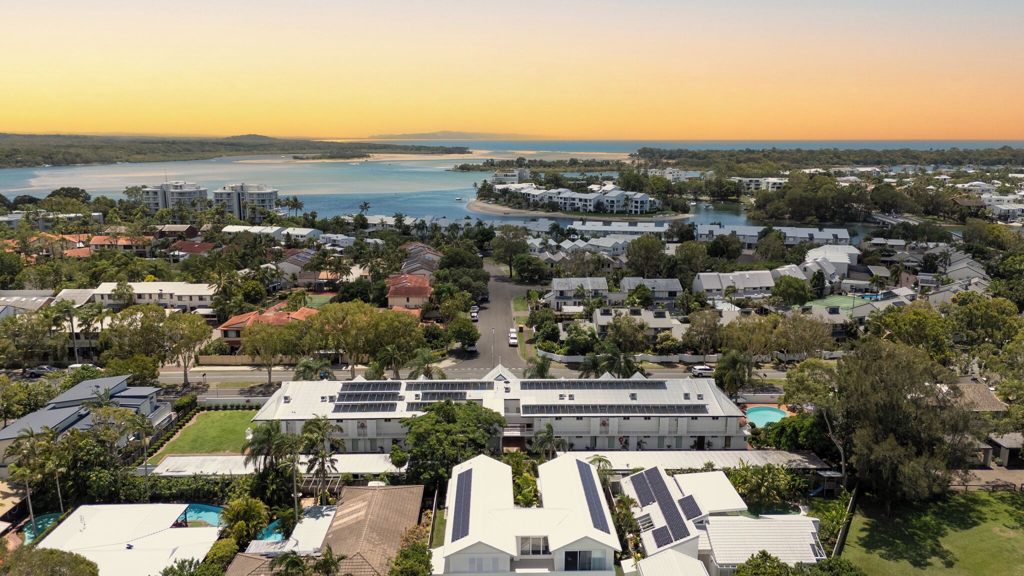 A residential area with houses, a swimming pool, and a view of the ocean.