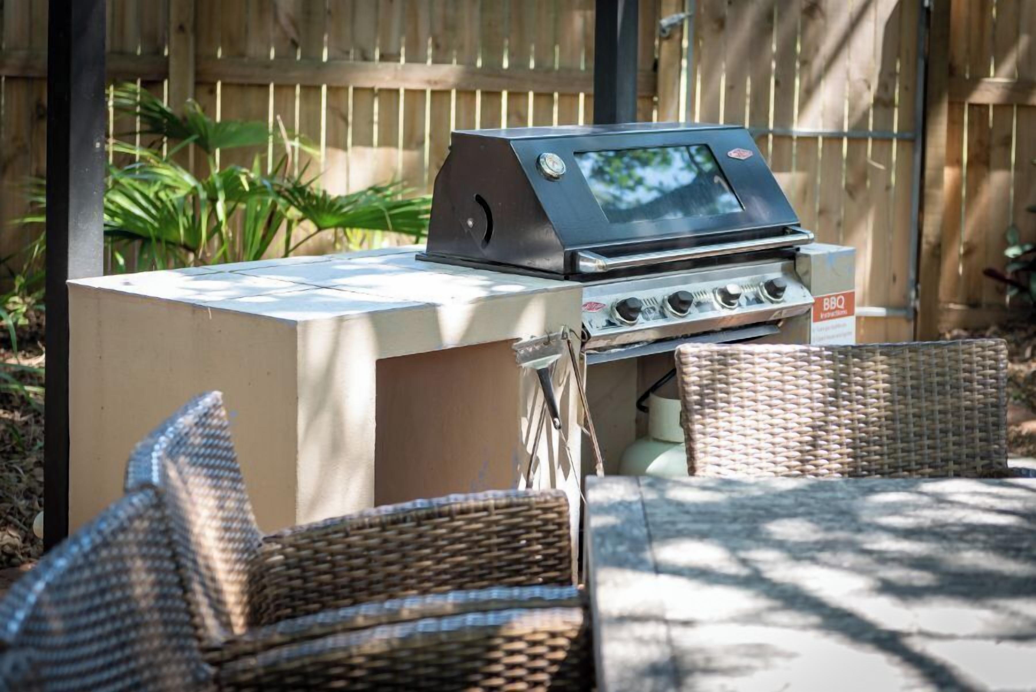 Una barbecue portatile su un tavolo pieghevole, con sedie in vimini.
