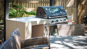 Una barbecue portatile su un tavolo pieghevole, con sedie in vimini.