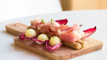 Een houten plank met eten, zoals gerookte zalm, kleine bolletjes en garnering.