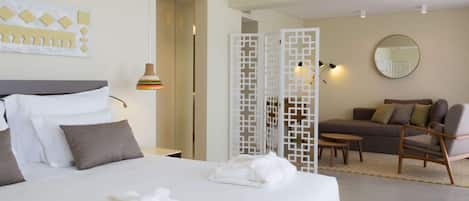 A hotel room with a large bed, a sofa, a small table, and a decorative screen.