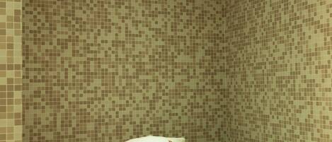 A tiled shower area with a bench and a towel.